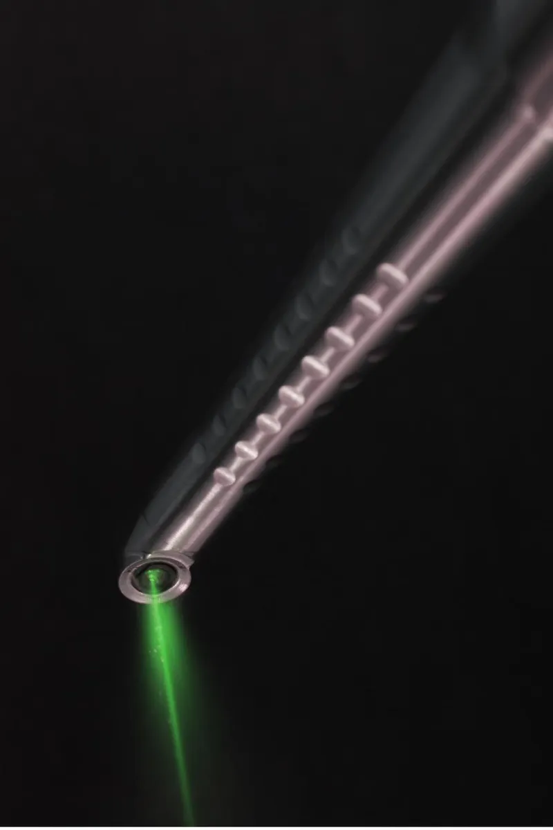 The Fotona laser handpiece firing its beam in a darkened treatment setting