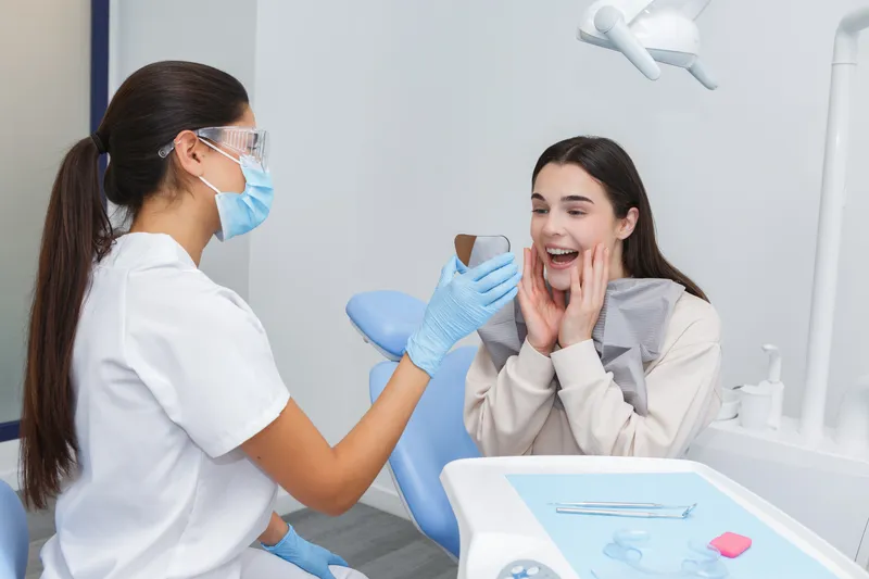 A dentist showing a patient the results in a hand mirror during a review appointment