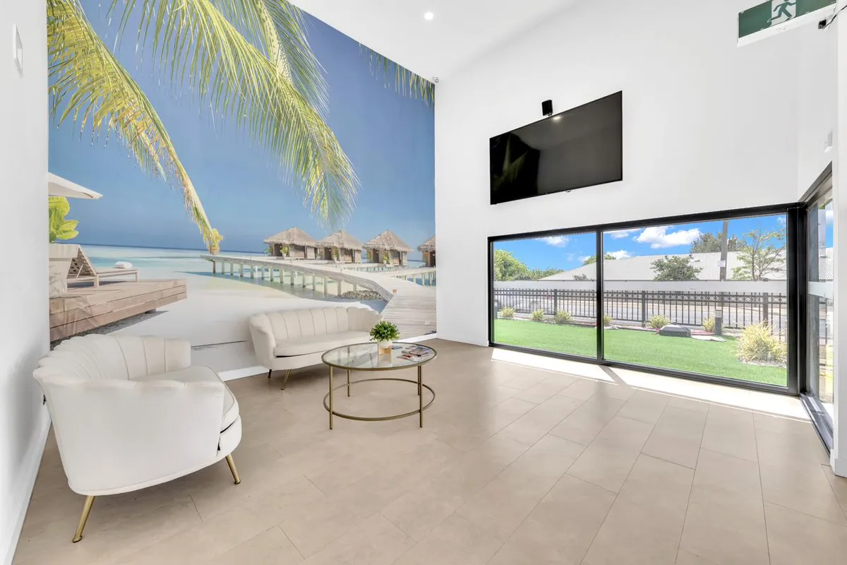 Waiting area with palm tree wall mural and natural light through floor-to-ceiling windows