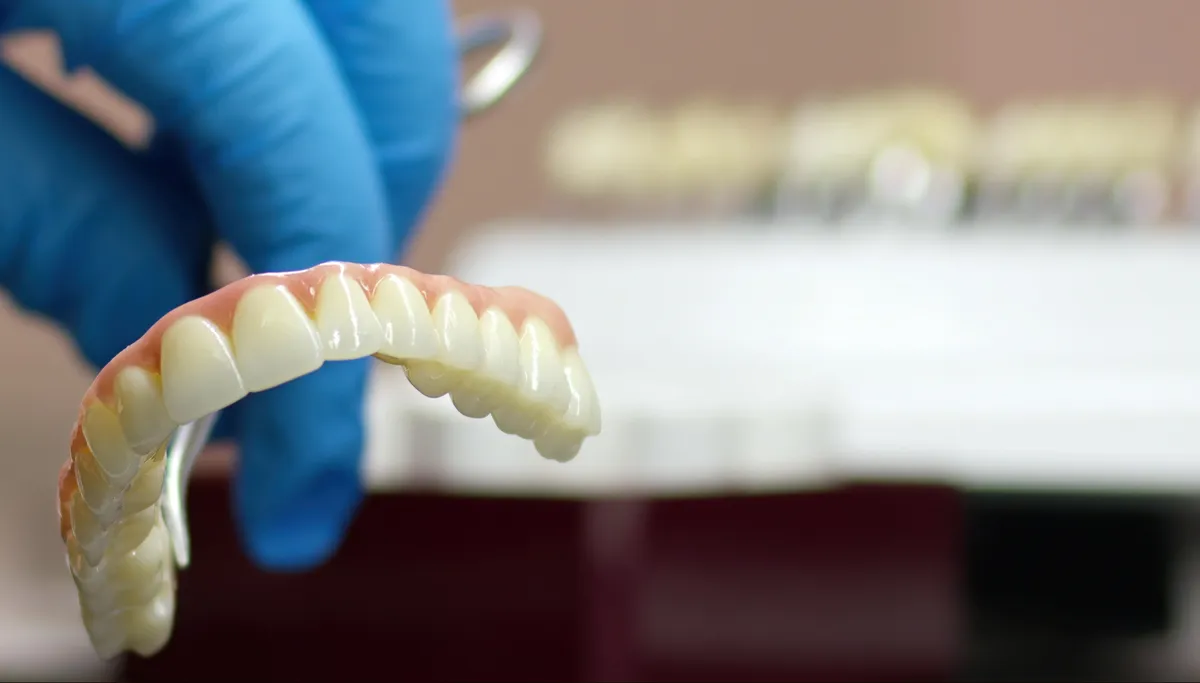 A full denture being checked on a tool in a dental lab