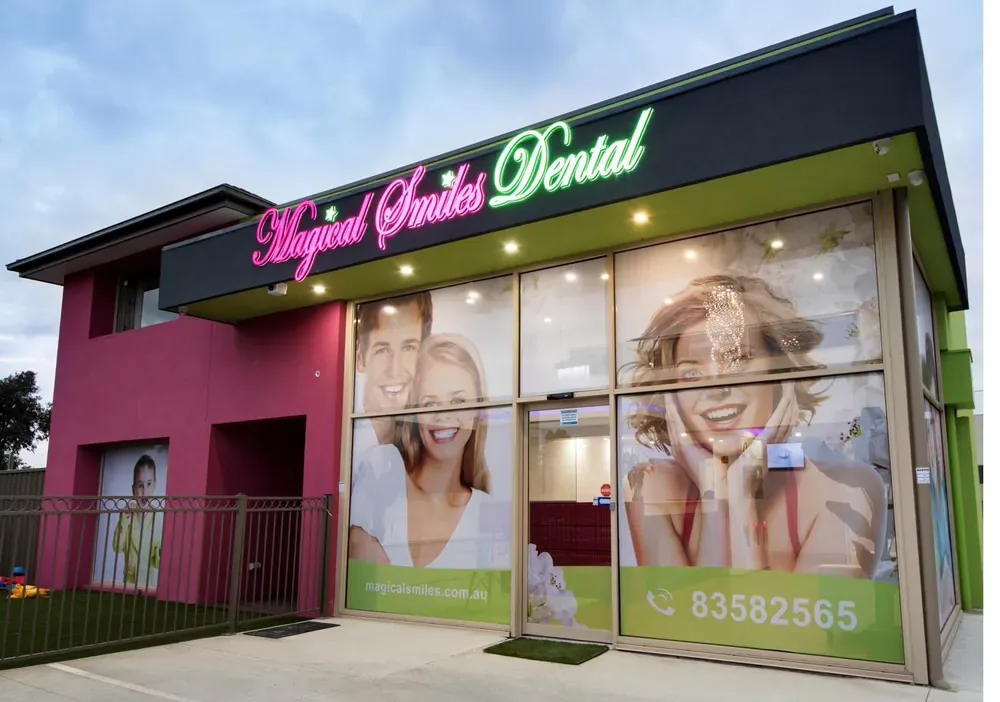 A Magical Smiles clinic exterior at dusk, with illuminated Magical Smiles Dental signage above large windows.