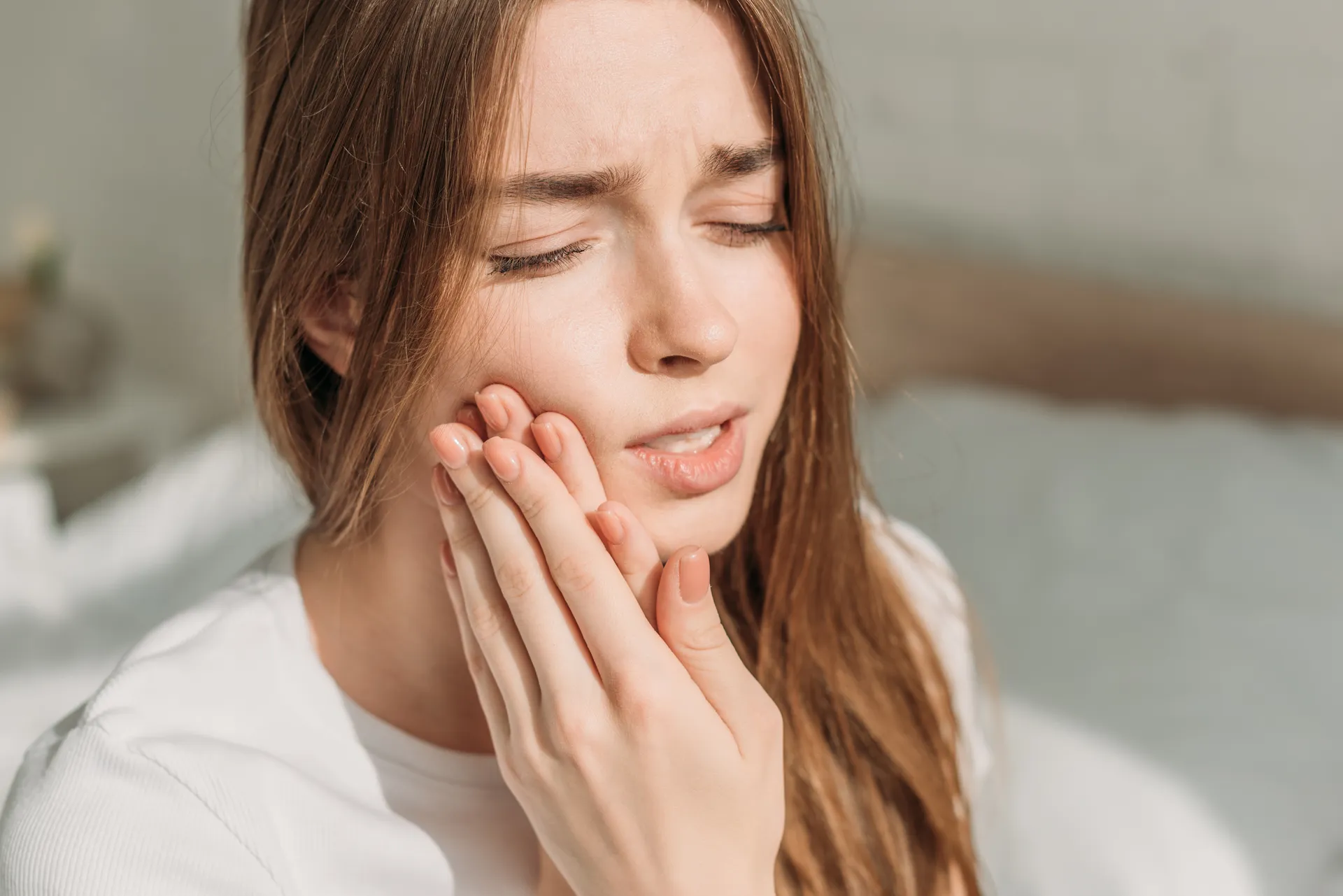 A woman holding her face in discomfort from sudden tooth pain
