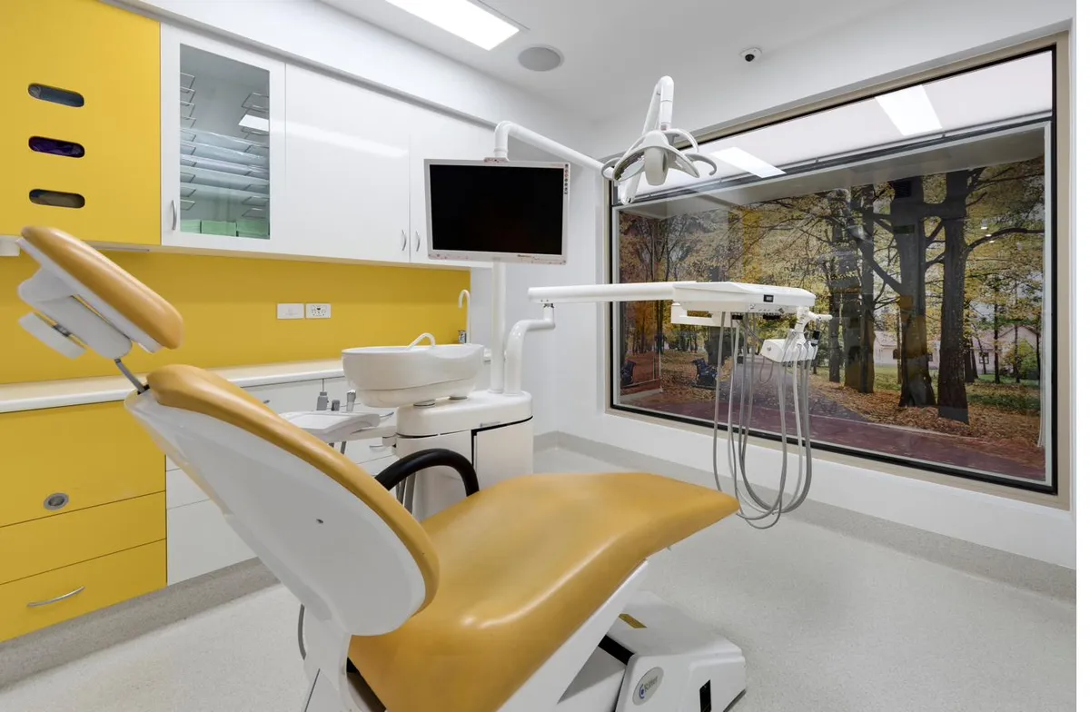 Warm, brightly-lit Magical Smiles treatment room with autumn trees through the window — calm, family-friendly setting for tongue and lip tie consultations